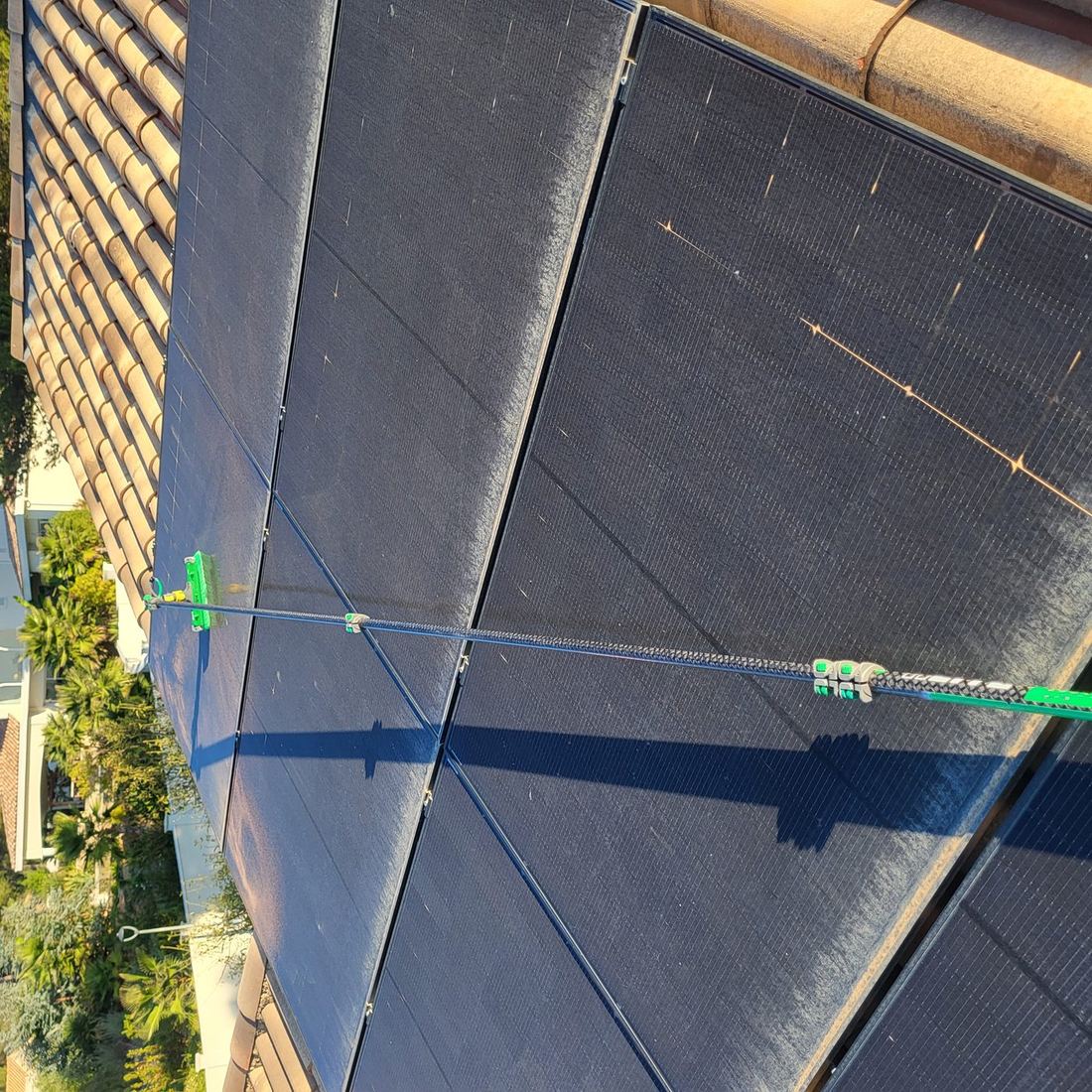 Brosse sur perche télescopique en train de nettoyer des panneaux photovoltaïques encrassés